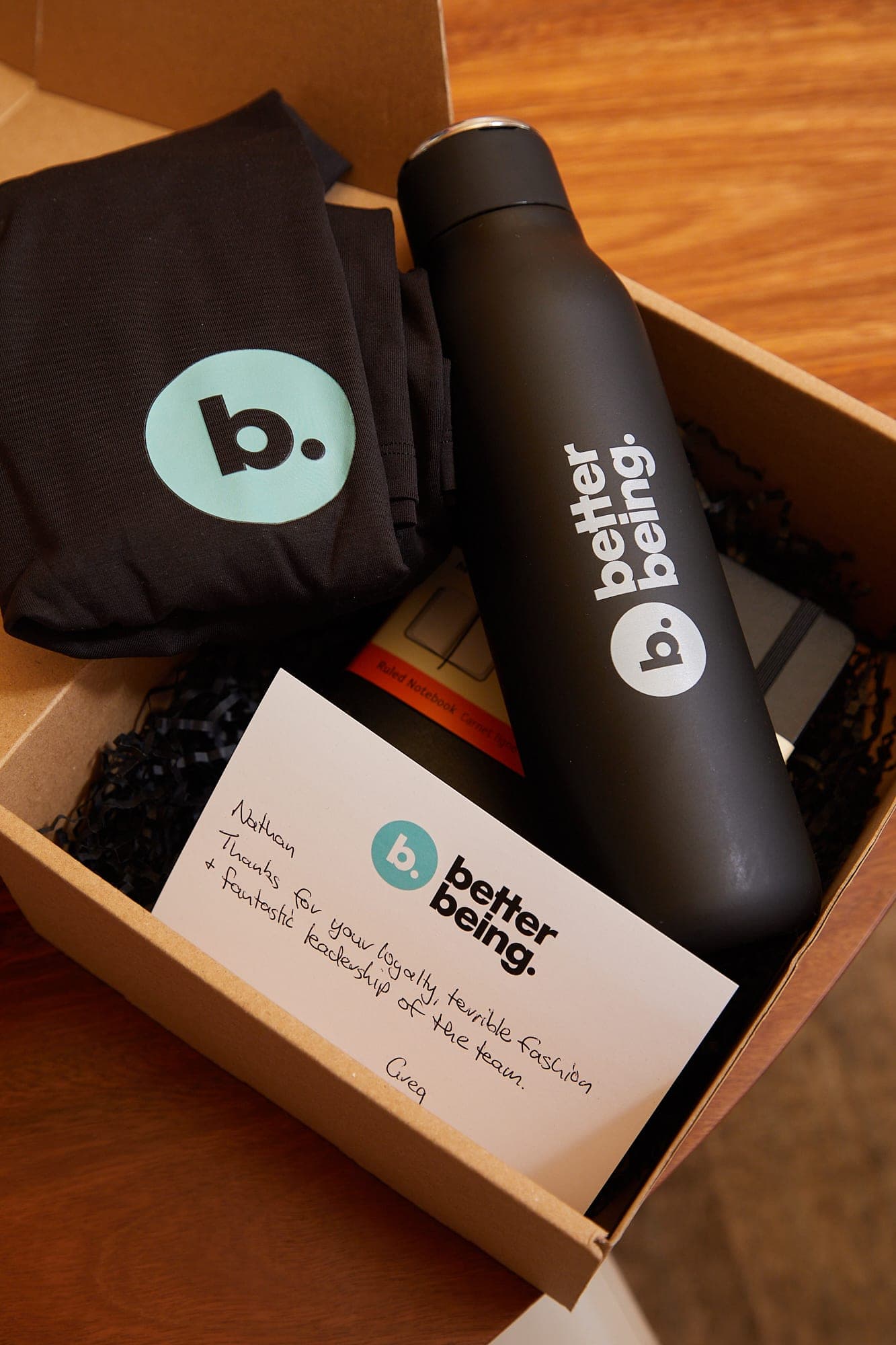 Employee onboarding kit with branded notebook, drink bottle and welcome card laid out in a box