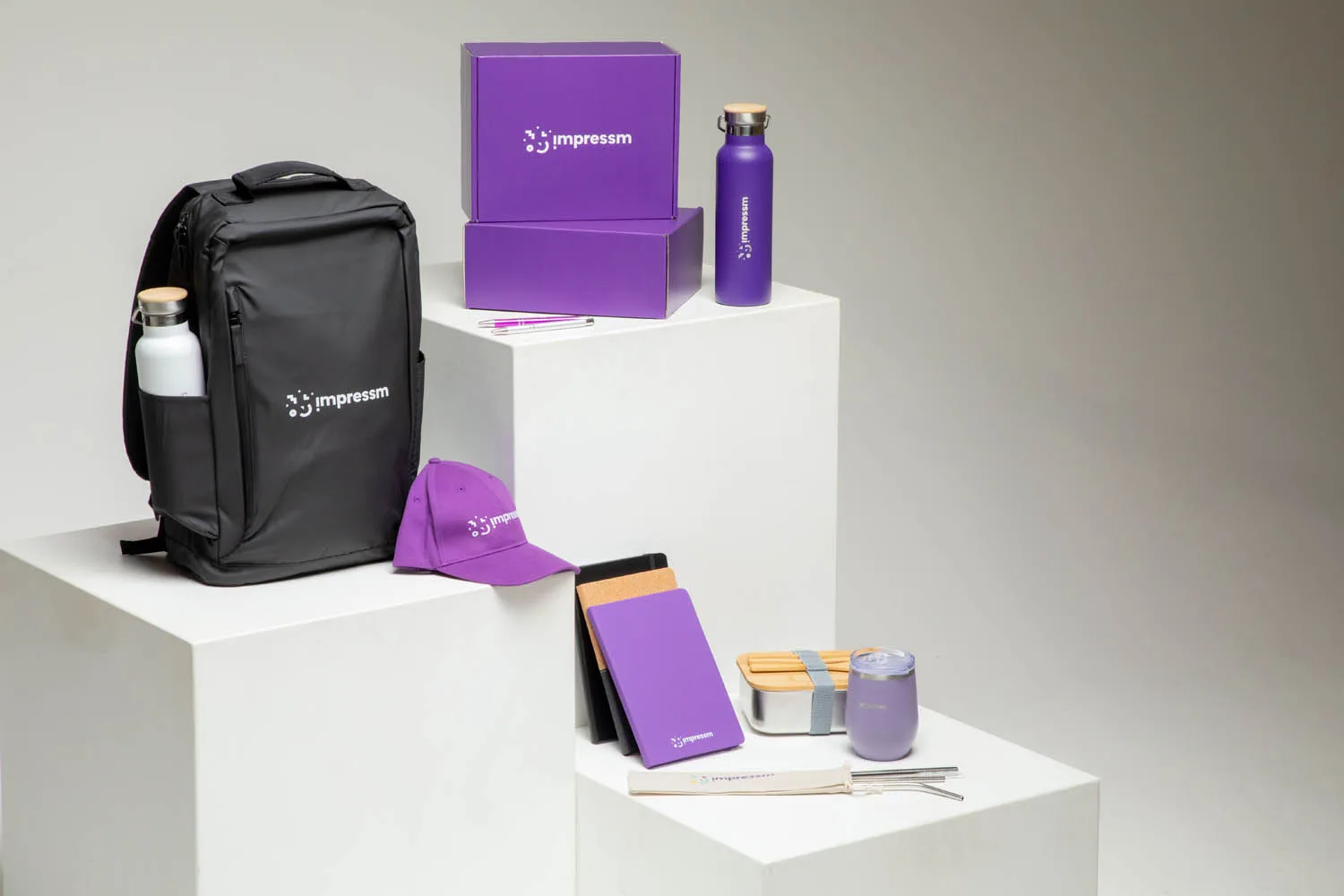 Impressm branded merch: backpack, boxes, bottle, cap and notebook